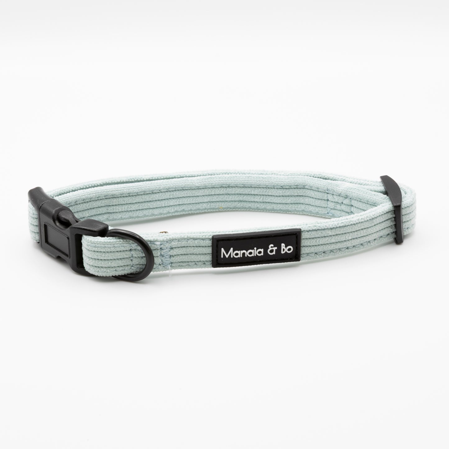 The Aqua Cord Dog Collar is light gray and adjustable for small to medium dogs, with a black plastic buckle, black metal ring, and a stitched Manala & Bo label. Shown on a plain white background.