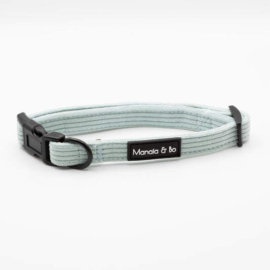 The Aqua Cord Dog Collar is light gray and adjustable for small to medium dogs, with a black plastic buckle, black metal ring, and a stitched Manala & Bo label. Shown on a plain white background.