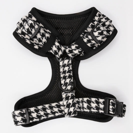 The Classic Houndstooth Dog Harness showcases a timeless black and white houndstooth pattern inspired by classic tweed, and features adjustable straps for a perfect fit, a breathable mesh lining for comfort, and a durable metal ring for secure leash attachment.