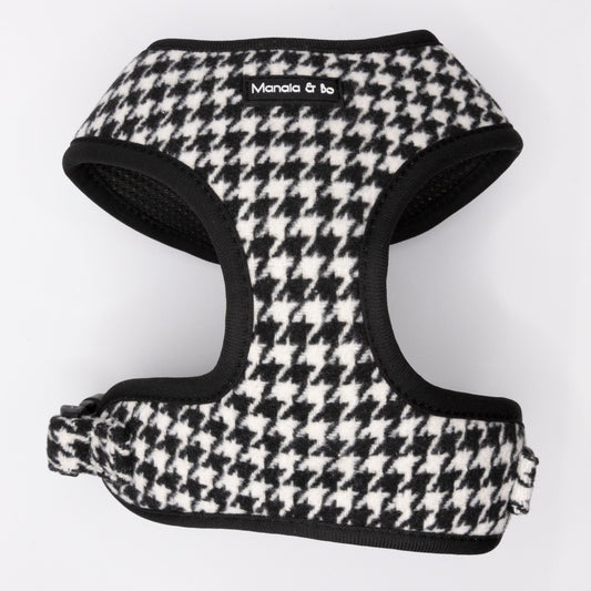 The Classic Houndstooth Dog Harness features a black and white houndstooth pattern with black trim and a "Manala & Bo" label on the front. This adjustable harness is displayed flat on a white background.