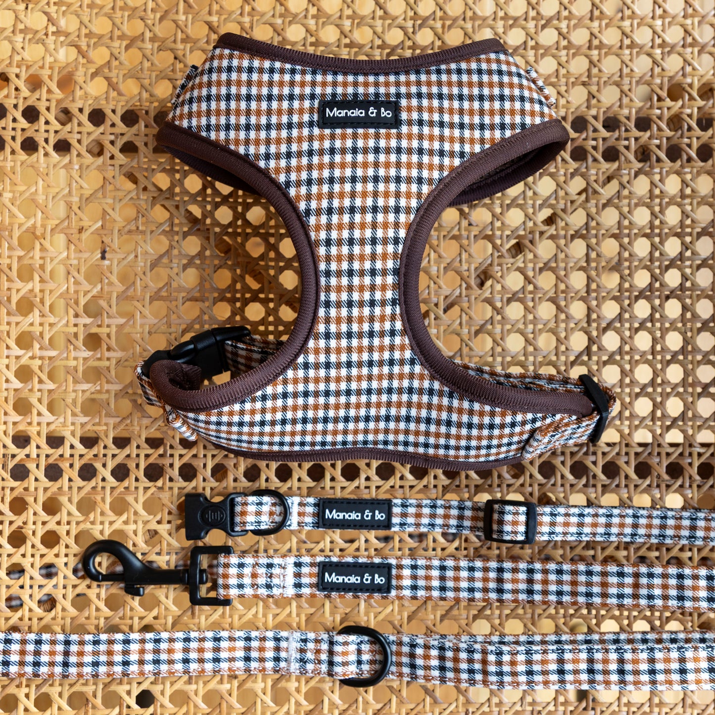 The Cocoa Heritage Lite Harness, Lead & Collar set features a brown, blue, and white plaid design, displayed on woven rattan. Each piece pairs perfectly together for a coordinated look.