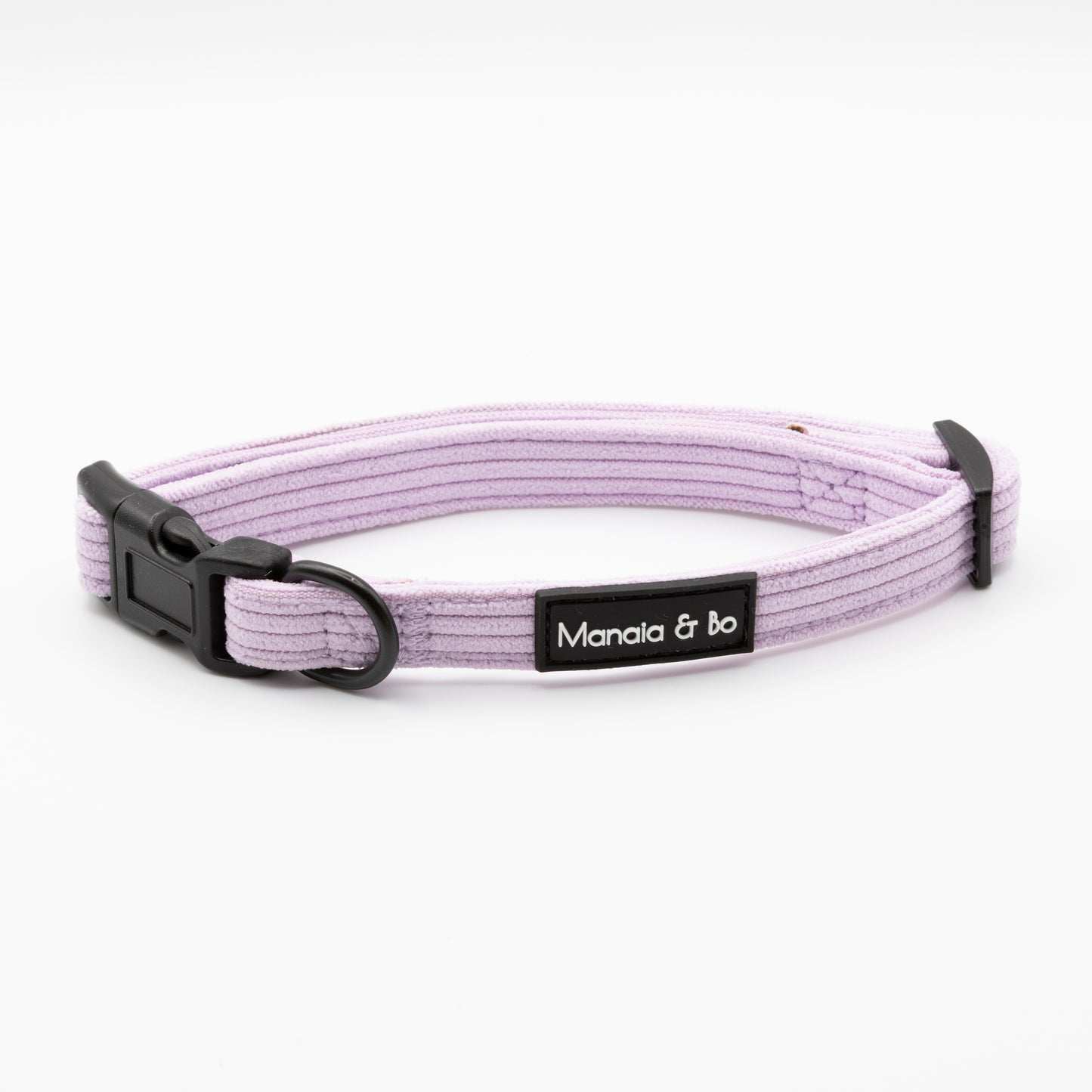The Lavender Cord Collar & Lead is a light purple ribbed adjustable dog collar with a black plastic buckle, metal D-ring, and a black "Manala & bo" label on the front, shown against a white background.