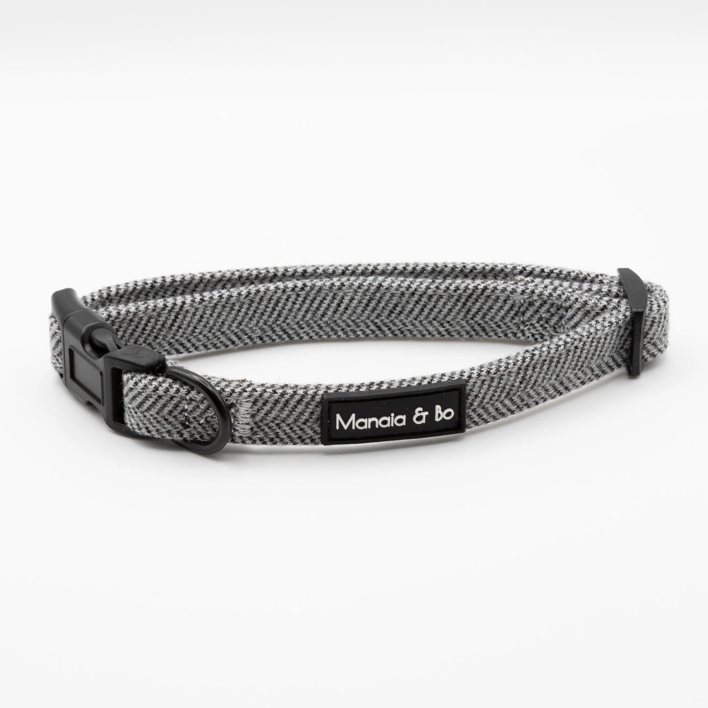 The Monochrome Tweed Collar & Lead features a gray and black design with a plastic buckle and a black Manaia & Bo tag. Shown on a white background, this adjustable collar blends style and function for your pet.