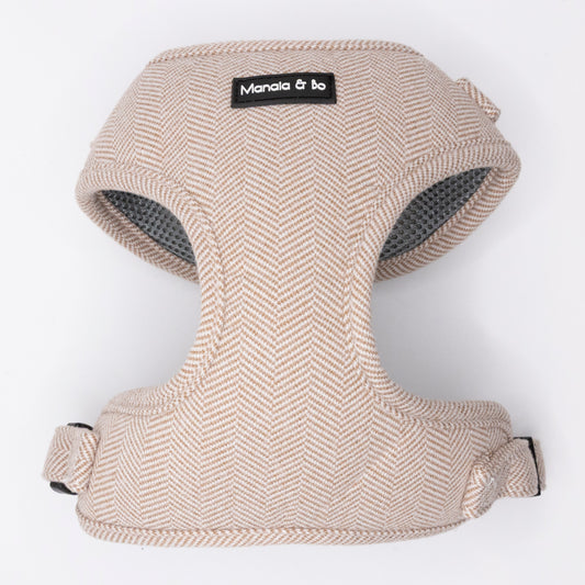 The Nougat Tweed Dog Harness, shown on a plain white background, is a beige herringbone fabric harness with adjustable straps and a black Manala & bo label on the front.