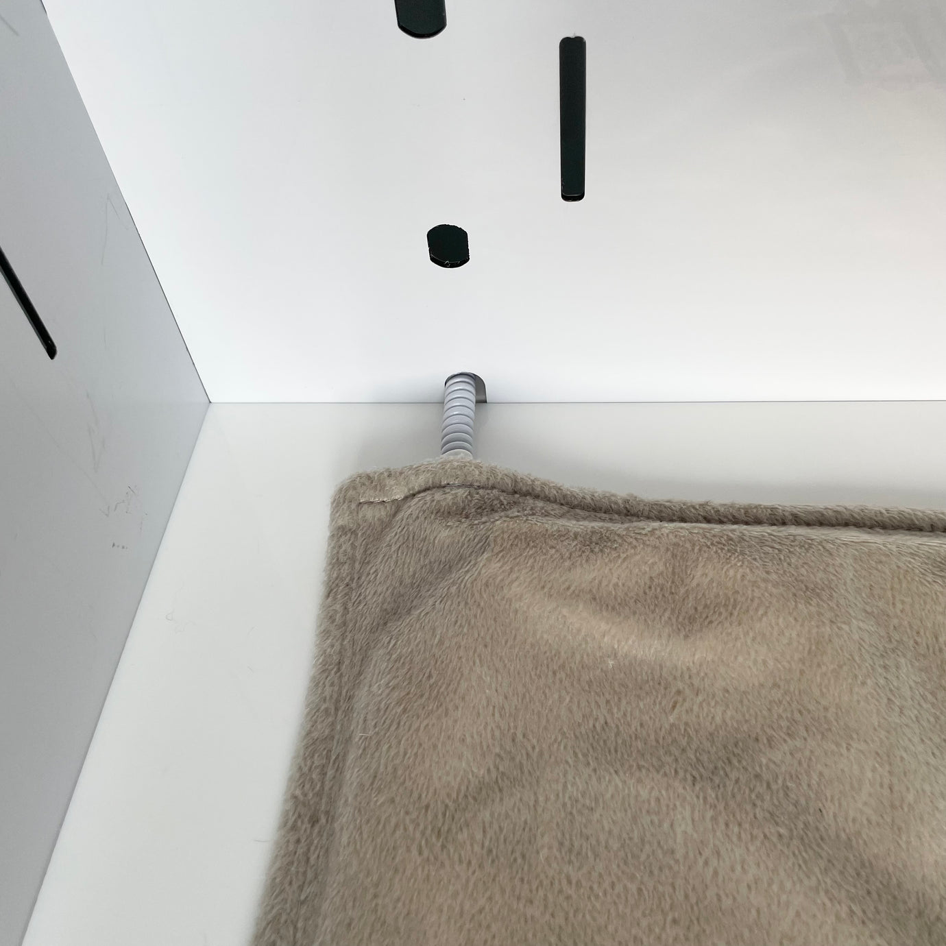 The Petpen Crate features vertical black slots, a spring-like metal rod on the back wall, and a soft beige blanket, creating a cozy minimalist space ideal for crate training or providing your pet with a tranquil den.