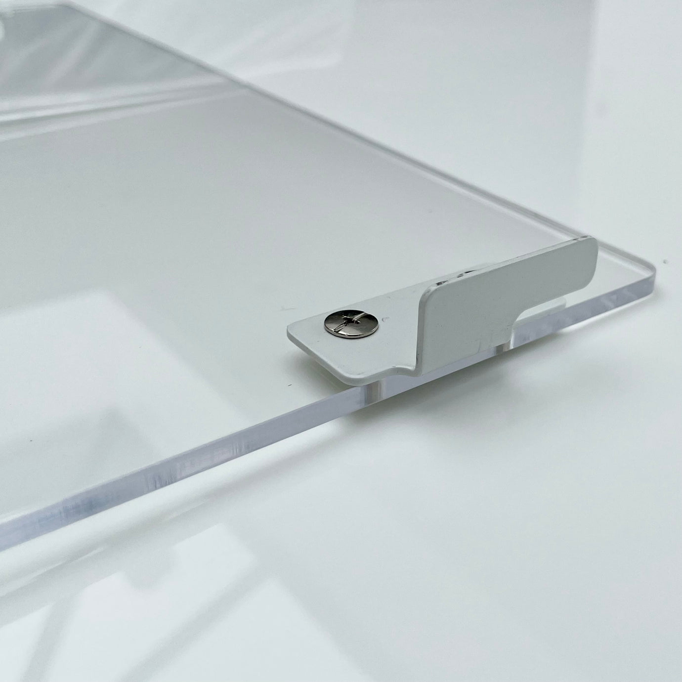A close-up of the Petpen Crate shows a clear acrylic sheet attached with a white metal bracket and screw, emphasizing its minimalist design on a glossy white surface.