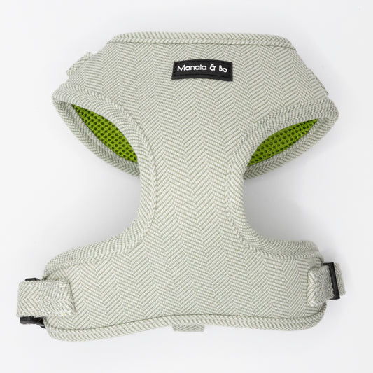 The Pine Tweed Dog Harness features light grey, textured pine tweed in a herringbone pattern, a Manala & bo label, green interior lining, adjustable straps, and black plastic buckles for comfort and a perfect fit.