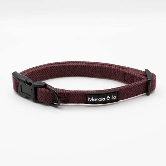 The Wild Plum Tweed Dog Collar features maroon tweed with a black plastic buckle, black metal ring, and a Manala & bo label, shown against a white background.