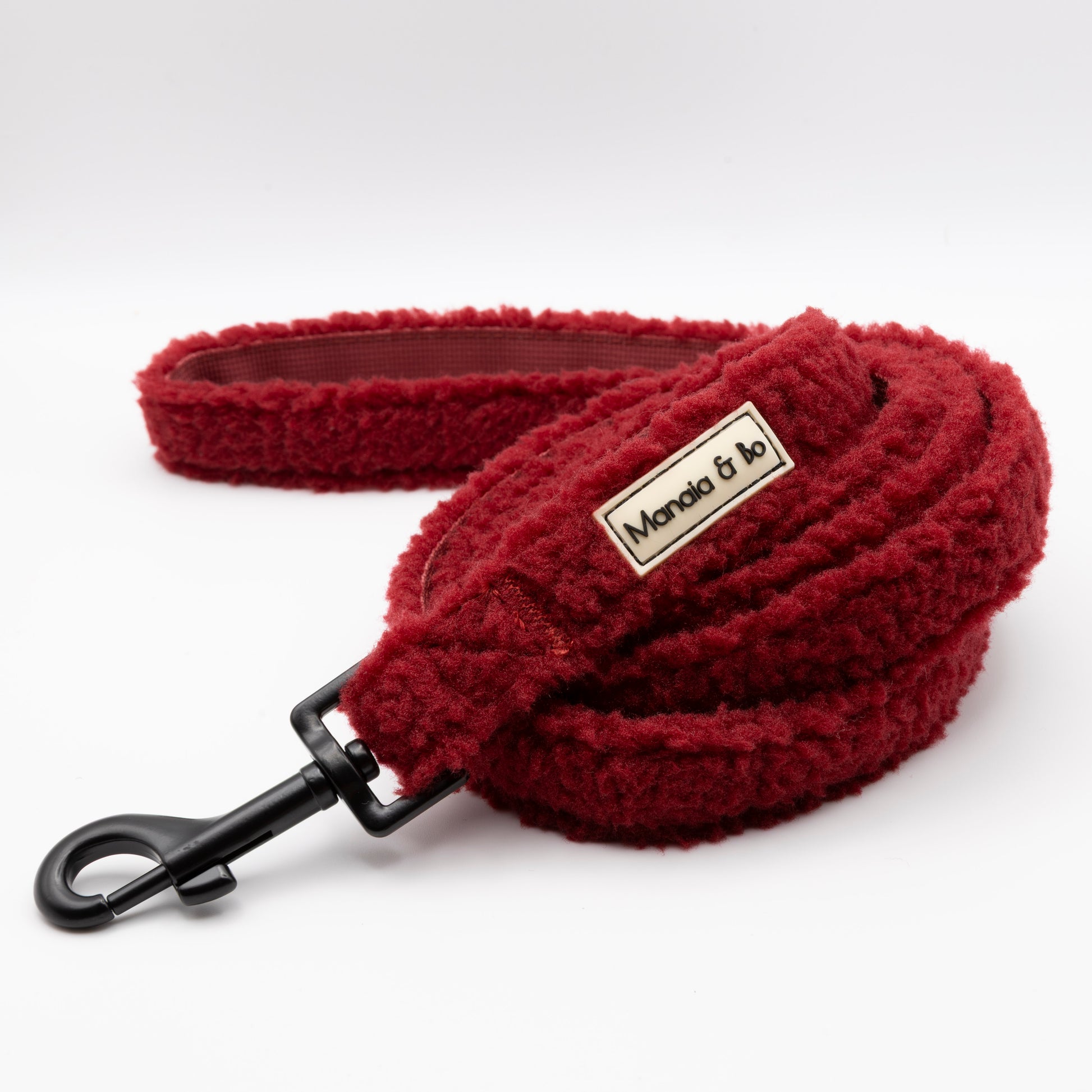 The Bordeaux Teddy Dog Lead in red features a fluffy design, black metal clip, and Marlo & Co label. This fixed-length lead offers comfort and style for daily walks, all shown on a plain white background.