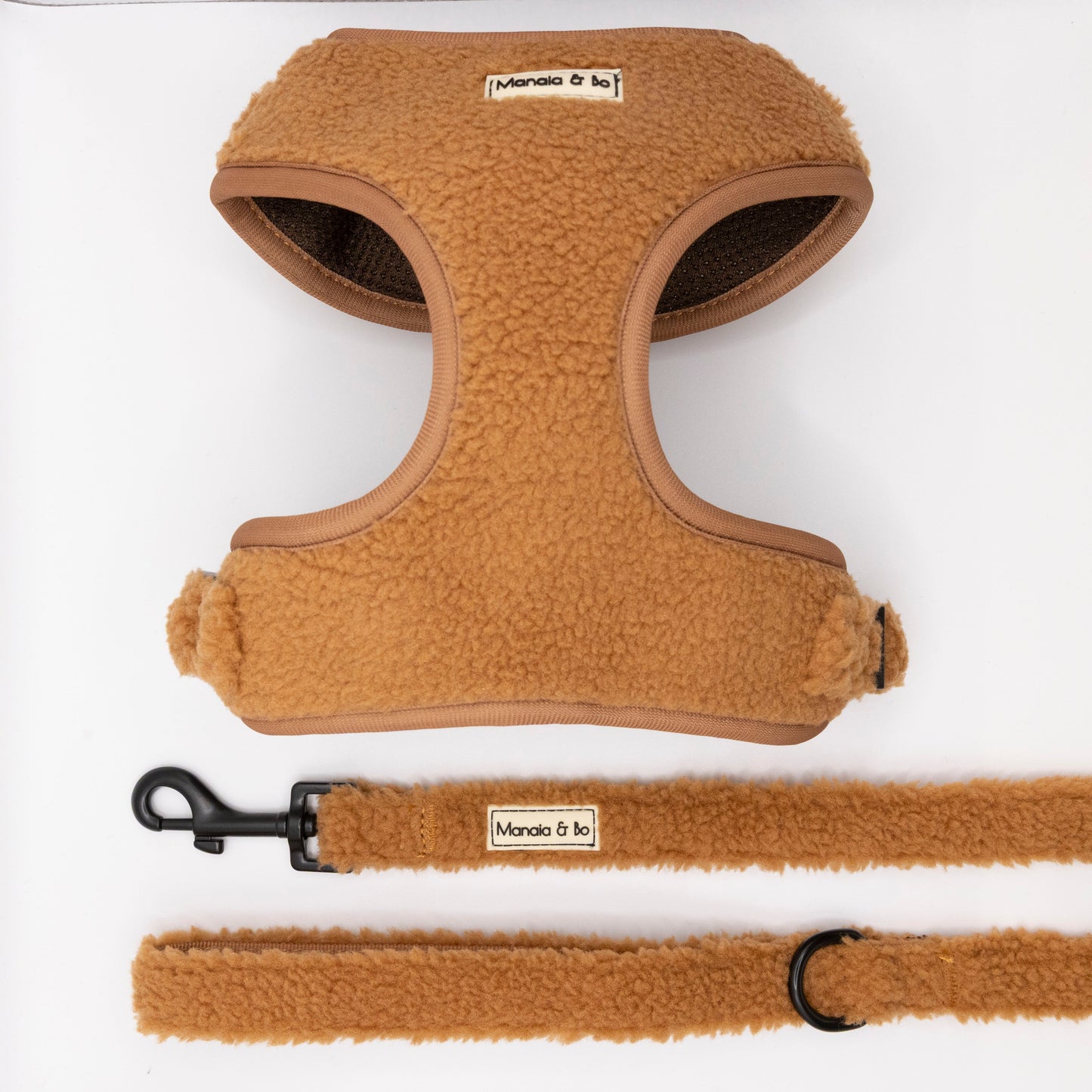 The Caramel Teddy Harness & Lead, featuring a tan fleece-lined, adjustable harness and matching lead with soft fluffy texture and a Moncia & Bo label, are shown on a white background. The leash includes a black metal clasp and ring.