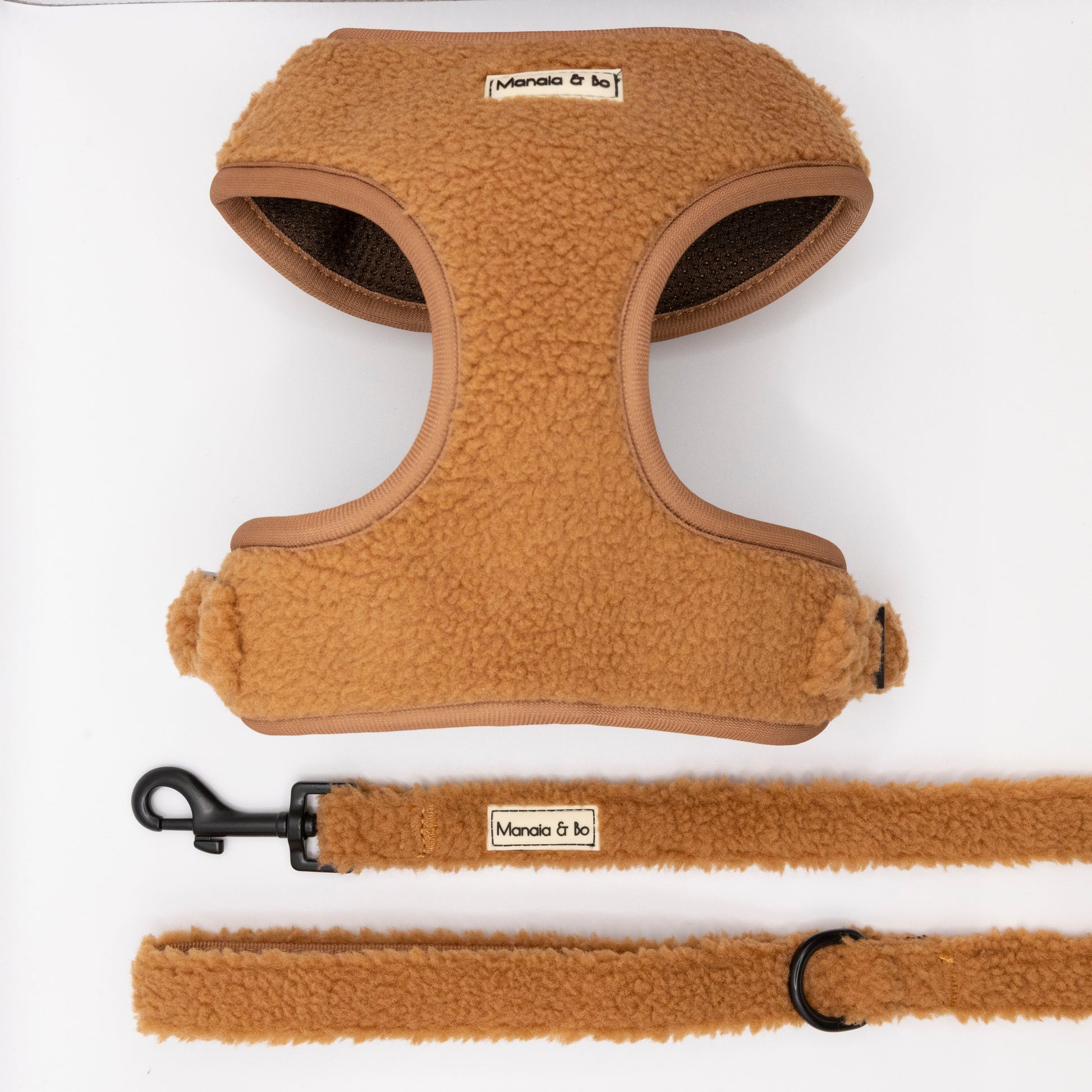 The Caramel Teddy Harness & Lead, featuring a tan fleece-lined, adjustable harness and matching lead with soft fluffy texture and a Moncia & Bo label, are shown on a white background. The leash includes a black metal clasp and ring.