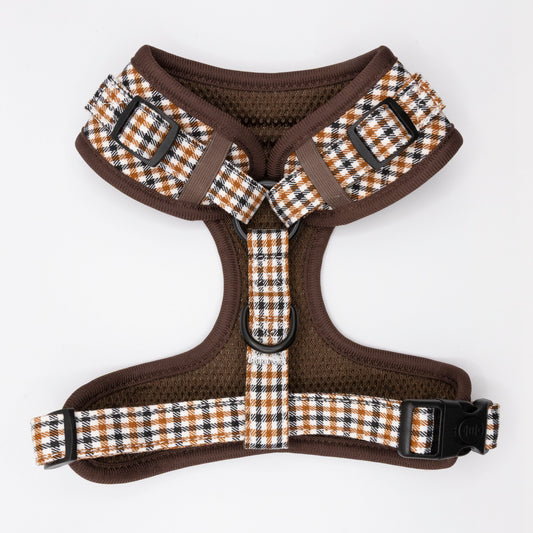 The Classic Houndstooth Dog Harness features adjustable straps, black trim, and a sturdy metal leash ring. Displayed on a white background, this harness offers a timeless style for your dog.