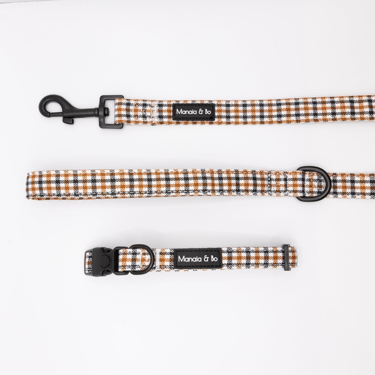The Cocoa Heritage Lite Collar & Lead is a matching checked-patterned set in black, white, and brown, featuring a lockable-buckle collar and adjustable lead with Moncia & bo labels on a white background.