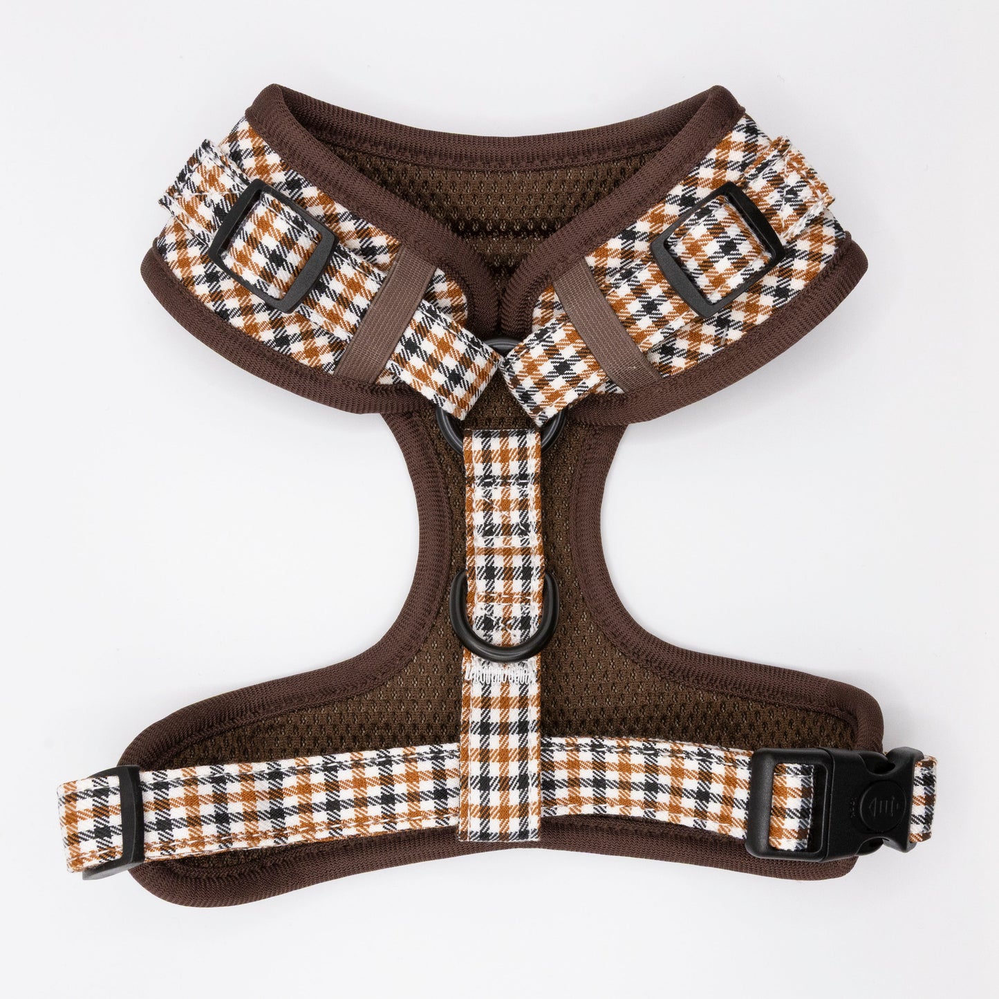 The Cocoa Heritage Lite Dog Harness, featuring a brown and white plaid design, adjustable straps, black buckles, and metal rings, is shown laid flat on a white background.