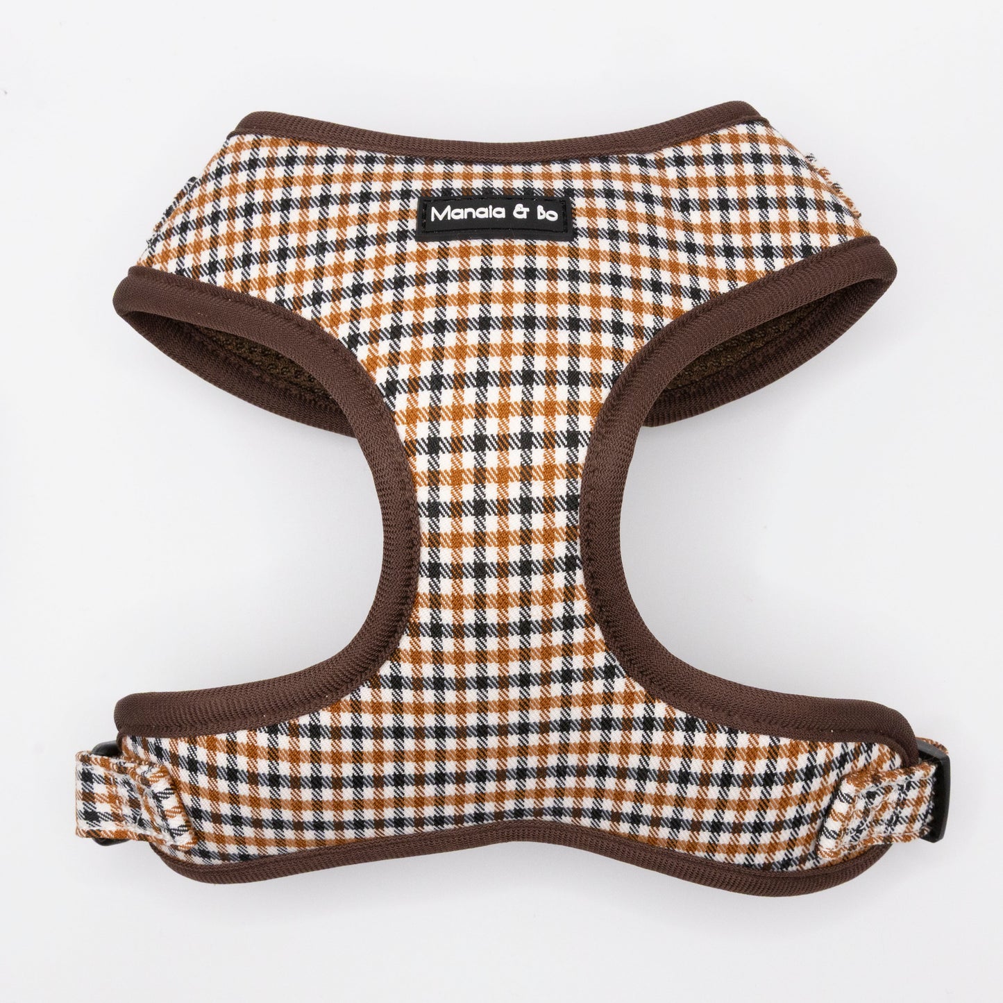 The Cocoa Heritage Lite Dog Harness features a brown, black, and white checkered pattern with brown trim and a black "Manala & bo" label. This lightweight, adjustable harness is shown on a white background.