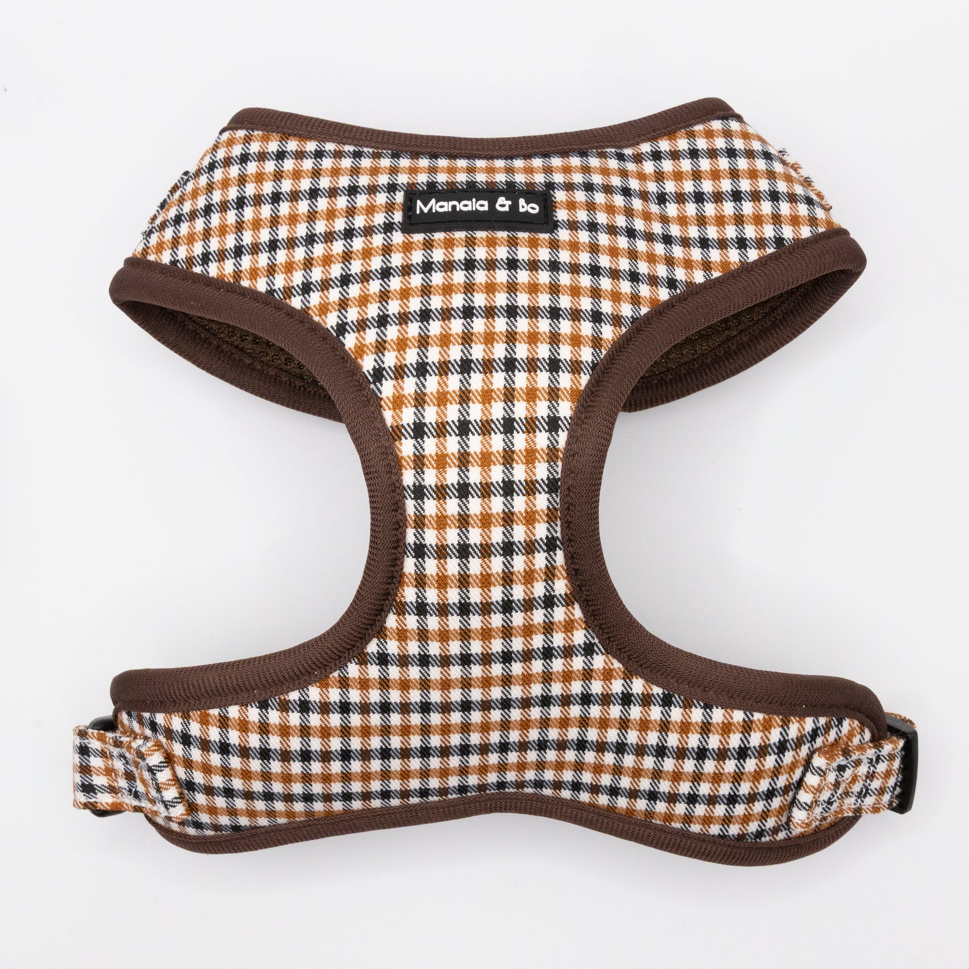 The Cocoa Heritage Lite Dog Harness features a brown, black, and white checkered pattern with brown trim and a black "Manala & bo" label. This lightweight, adjustable harness is shown on a white background.