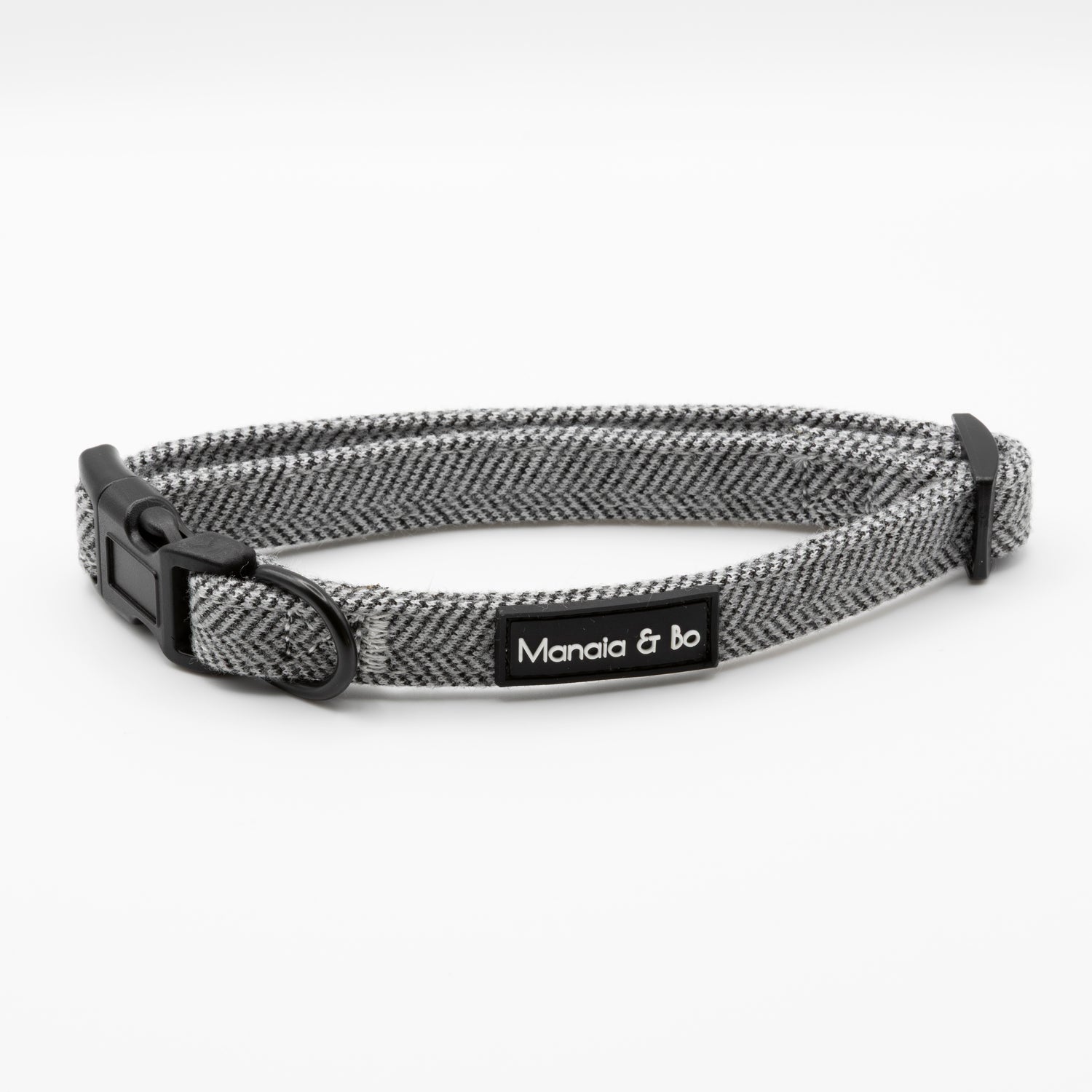 The Monochrome Tweed Collar & Lead features a gray and black design with a plastic buckle and a black Manala & bo tag. Shown on a white background, this adjustable collar blends style and function for your pet.