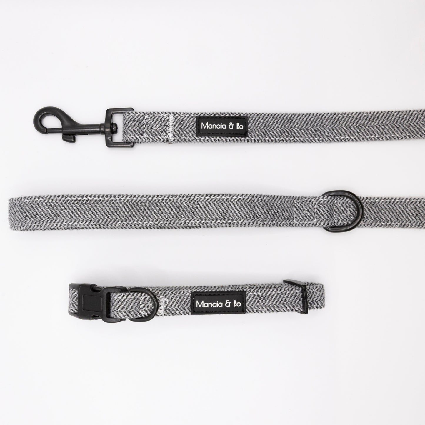 The Monochrome Tweed Collar & Lead, featuring a grey herringbone pattern, black hardware, and a Mania & Ko label, are displayed on a white background.