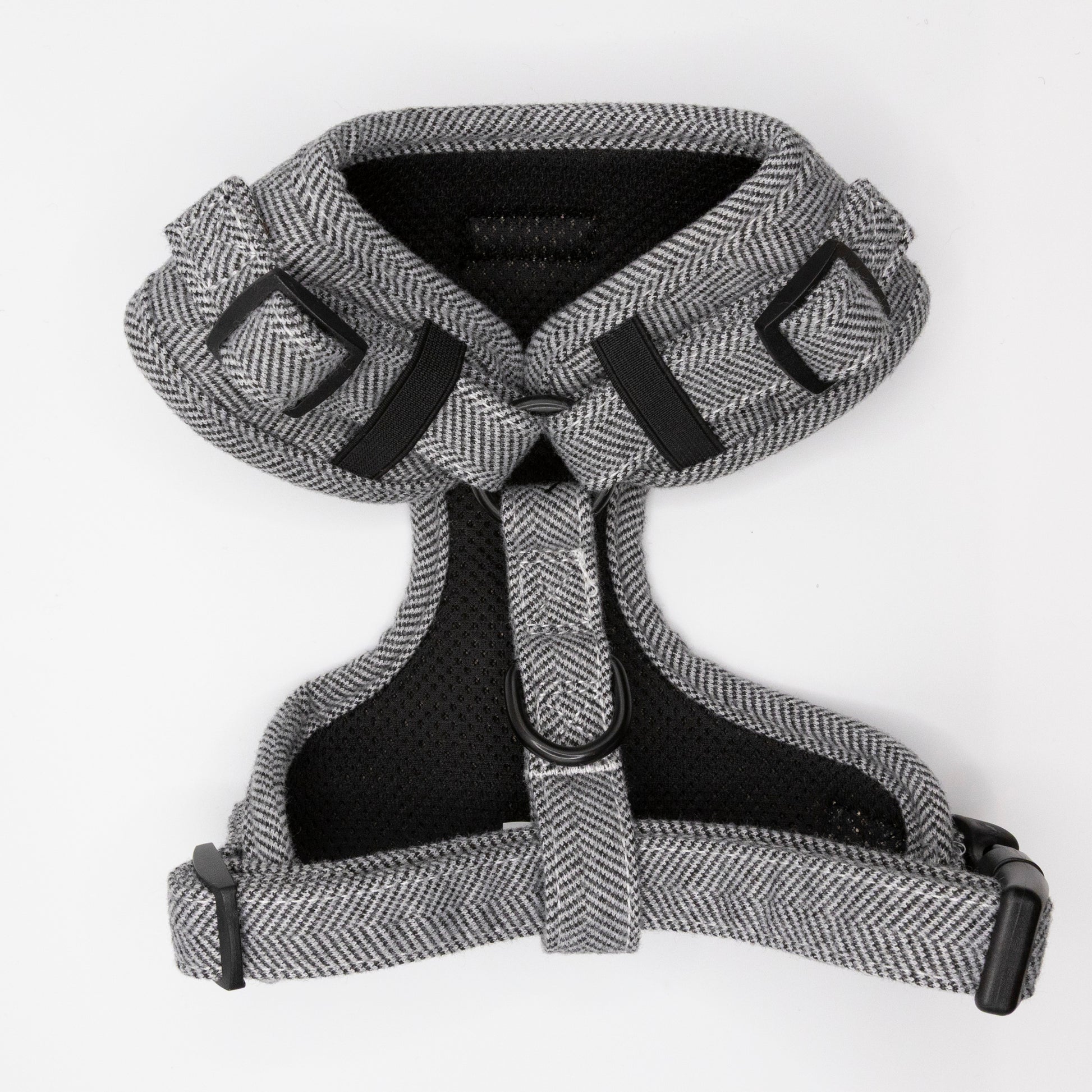The Monochrome Tweed Harness & Lead, a gray herringbone-patterned adjustable dog harness with black buckles and straps for small to medium dogs, is displayed flat on a white background.