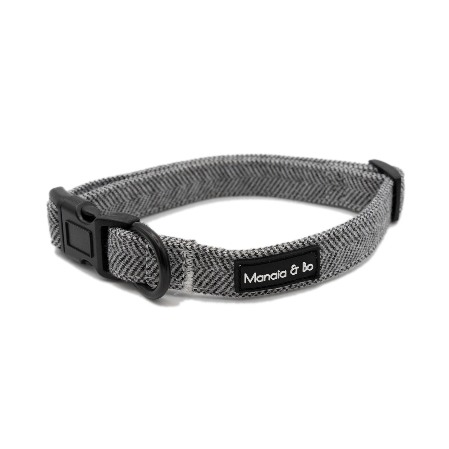 Monochrome (dark grey and white) tweed herringbone adjustable dog collar on a white background from the front. The collar is opened almost in a circle with the fixing ring in the foreground.