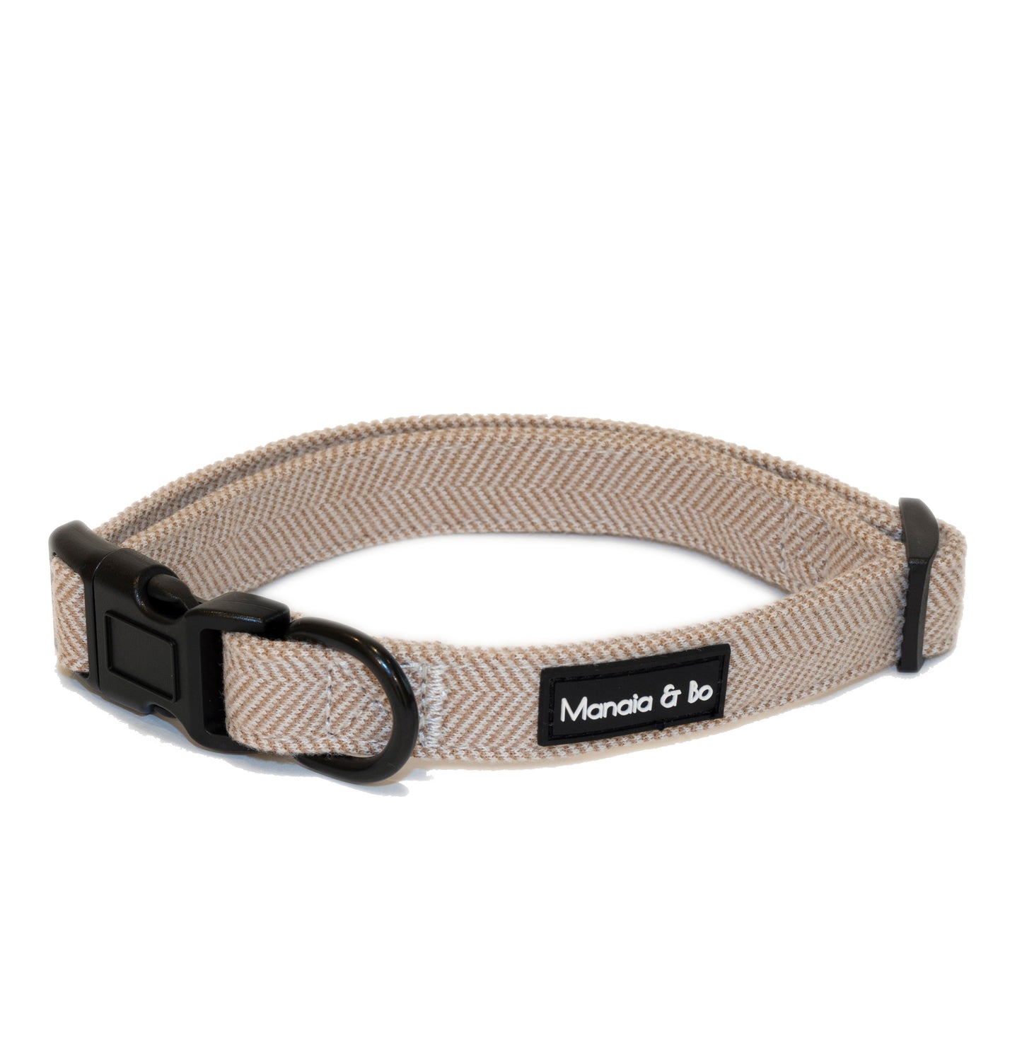 The Nougat Tweed Collar is a light brown herringbone-patterned dog collar made from quality materials, featuring a black buckle, D-ring, offering comfort and style.