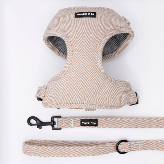 The Nougat Tweed Harness & Lead set, in a beige herringbone pattern, is laid out on a white background. The adjustable harness has black Moncia & bo labels, and the matching lead features a black clasp and metal ring.