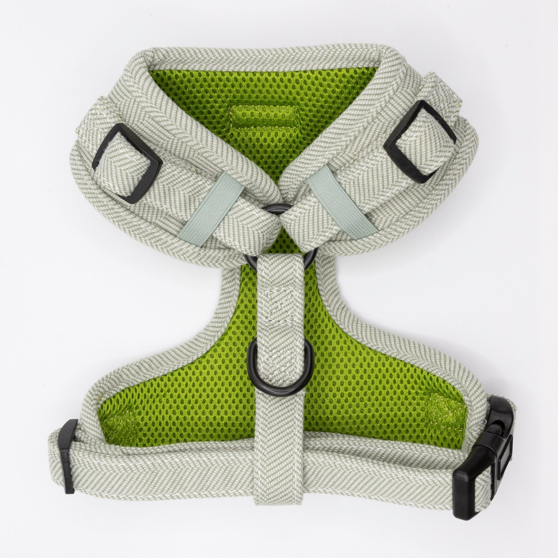 The Pine Tweed Dog Harness features light gray and green tweed, comfortable padding, adjustable straps, black plastic buckles, and metal rings for a secure and stylish fit. Shown laid flat on a white background.
