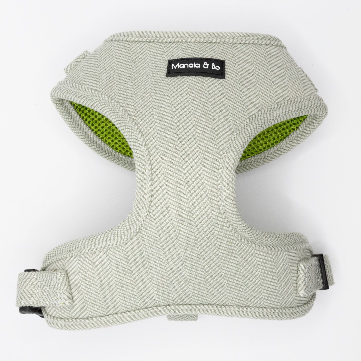 The Pine Tweed Dog Harness features light grey, textured pine tweed in a herringbone pattern, a Manala & bo label, green interior lining, adjustable straps, and black plastic buckles for comfort and a perfect fit.
