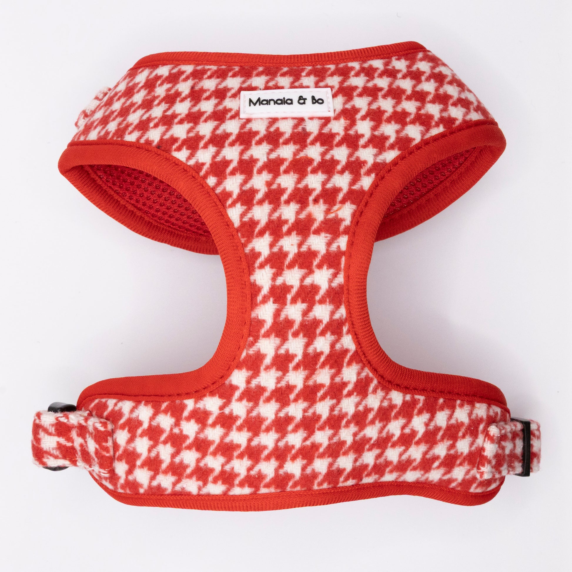 The Scarlet Houndstooth Harness & Lead is a red and white houndstooth-patterned tweed harness with a black buckle and a white "Manala & bo" label, offering your pup classic style and adjustable, secure comfort.