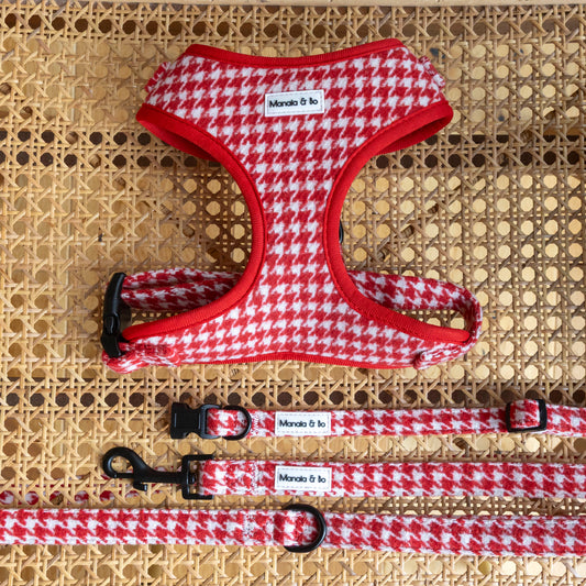 The Scarlet Houndstooth Harness, Lead & Collar set features a red and white houndstooth pattern with black clasps. Displayed on woven rattan, each piece bears the Monada & To label.