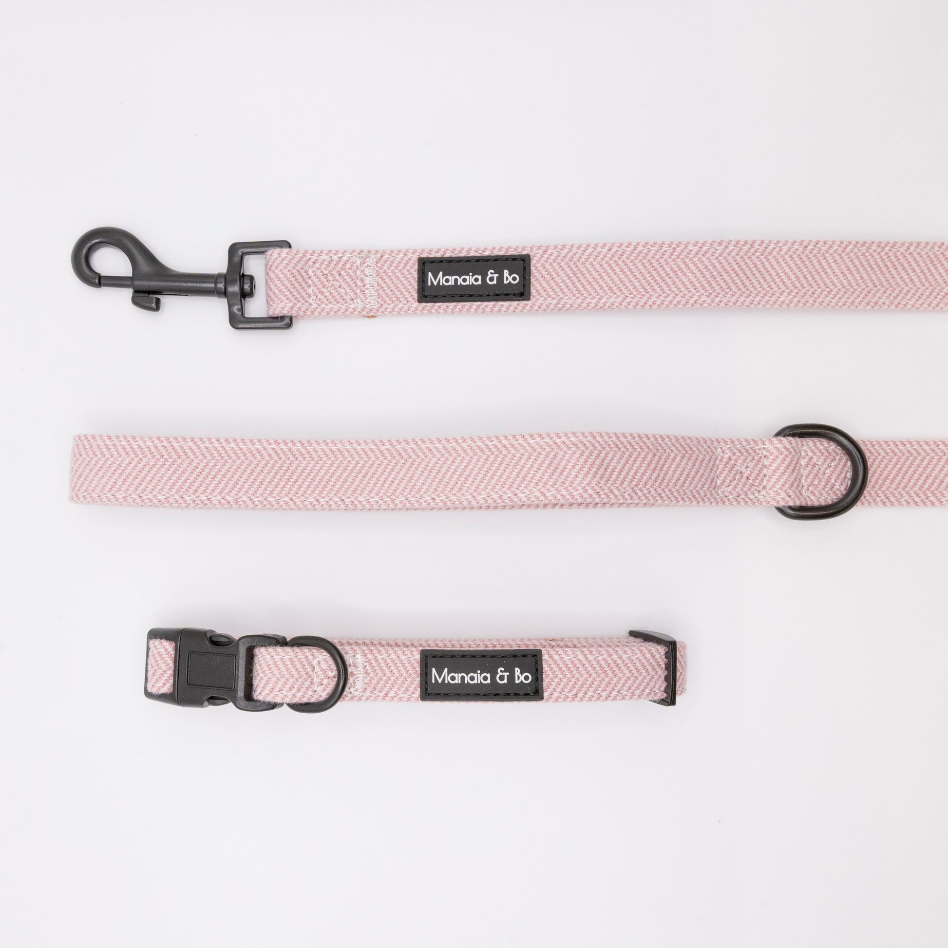 The Tea Rose Tweed Collar & Lead, a light pink adjustable dog collar and matching leash with black hardware labeled Manola & bo, are displayed flat on a white background.