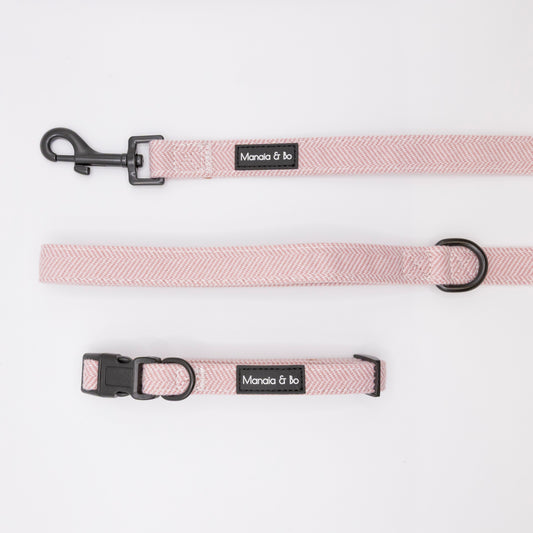 The Tea Rose Tweed Collar & Lead, a light pink adjustable dog collar and matching leash with black hardware labeled Manola & bo, are displayed flat on a white background.